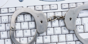 White keyboard with pair of closed handcuffs on top